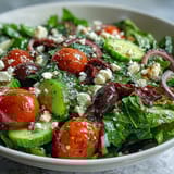 Fresh Mediterranean salad bowl featuring colorful vegetables, briny olives, and creamy feta, drizzled with zesty homemade Greek dressing.  
