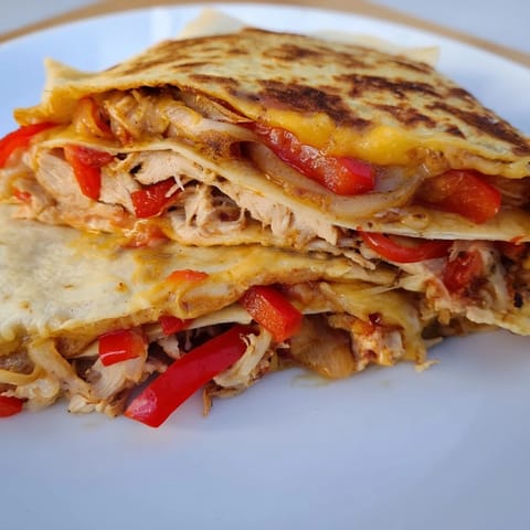 Golden-brown Chicken Quesadilla, filled with melted cheese, peppers, and chicken, ready to be sliced, inviting flavors.