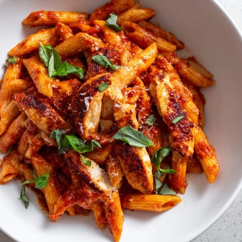 A close-up of Spicy Tomato Chicken Pasta, featuring al dente penne tossed in zesty tomato sauce with juicy chicken pieces.