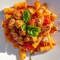 Tender chicken and al dente penne in a vibrant tomato basil sauce, garnished with fresh basil and Parmesan.