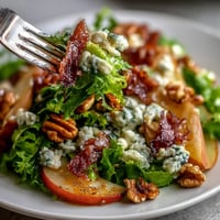 A vibrant salad bowl with frisée, ripe pears, crumbled blue cheese, and crispy prosciutto, drizzled with tangy vinaigrette.
